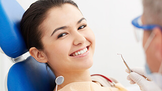 Young woman in dental chair smiling at dentist