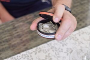 hand holding tin of tobacco pouches 